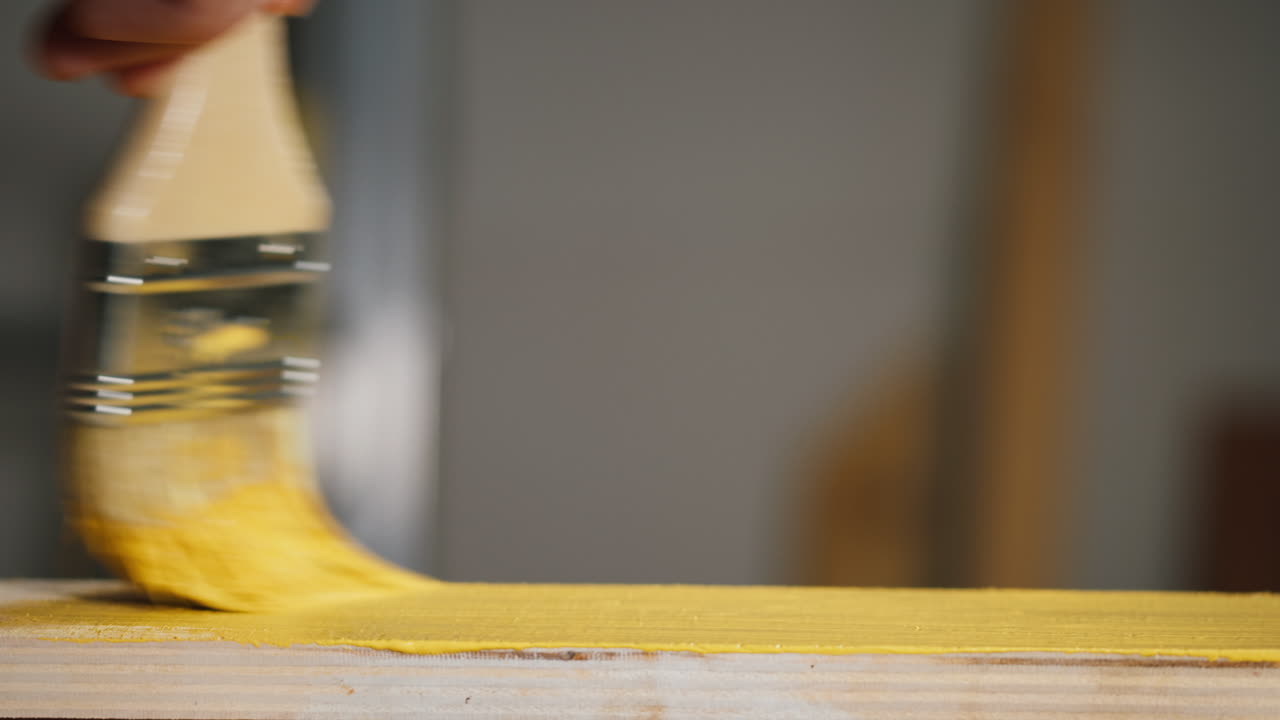 Close-up of Hand Painting Wooden Board with Yellow Paintbrush