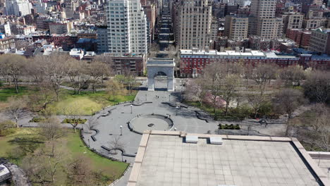 a high angle view over washington square park in nyc. the drone camera dollys out - up, away from the washington square arch. the camera then tilts up to look up fifth avenue - there is no traffic.
