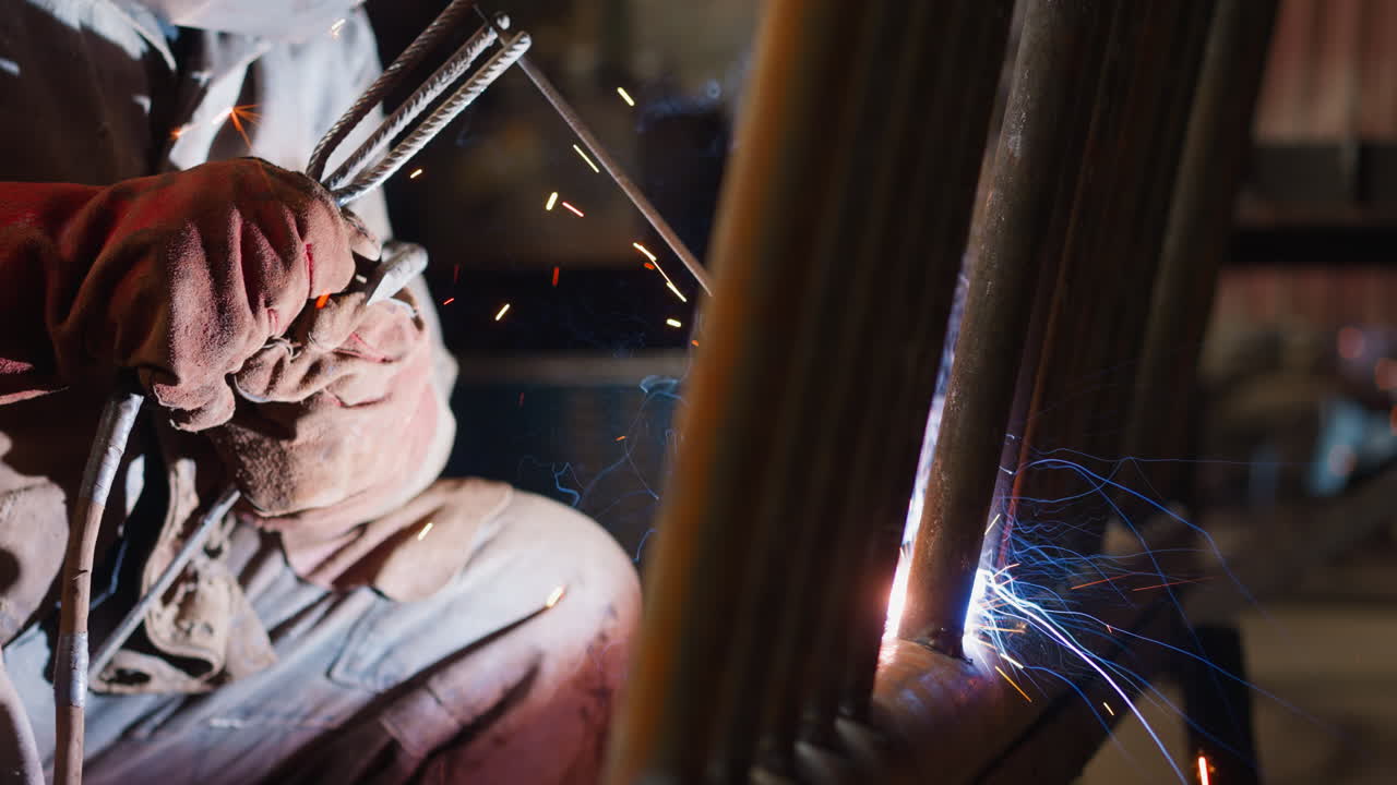 Worker in gloves welds steel pipeline with torch in workshop