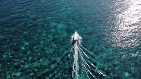 aerial video captures a boat gliding over clear turquoise waters, creating dynamic ripples
