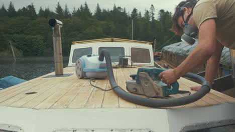 carpenter sanding down roof planks of wooden liveaboard boat