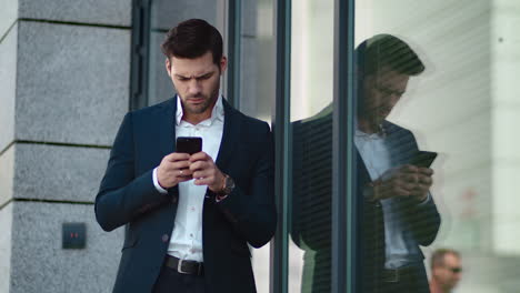 hombre de negocios de cerca de pie cerca del edificio. hombre de negocios usando un teléfono inteligente afuera