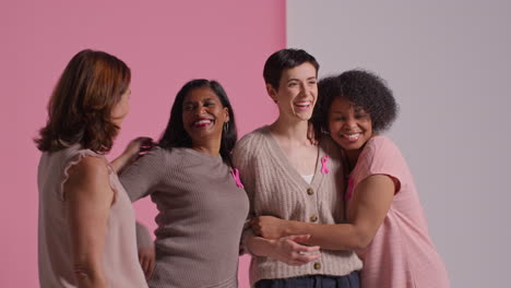 Studio-Portrait-Of-Multi-Racial-Group-Of-Women-Of-Different-Ages-Wearing-Pink-Breast-Cancer-Awareness-Ribbons-Hugging-Against-Pink-Background-1