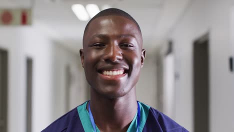 retrato de video de un trabajador médico afroamericano sonriente de pie en el pasillo del hospital