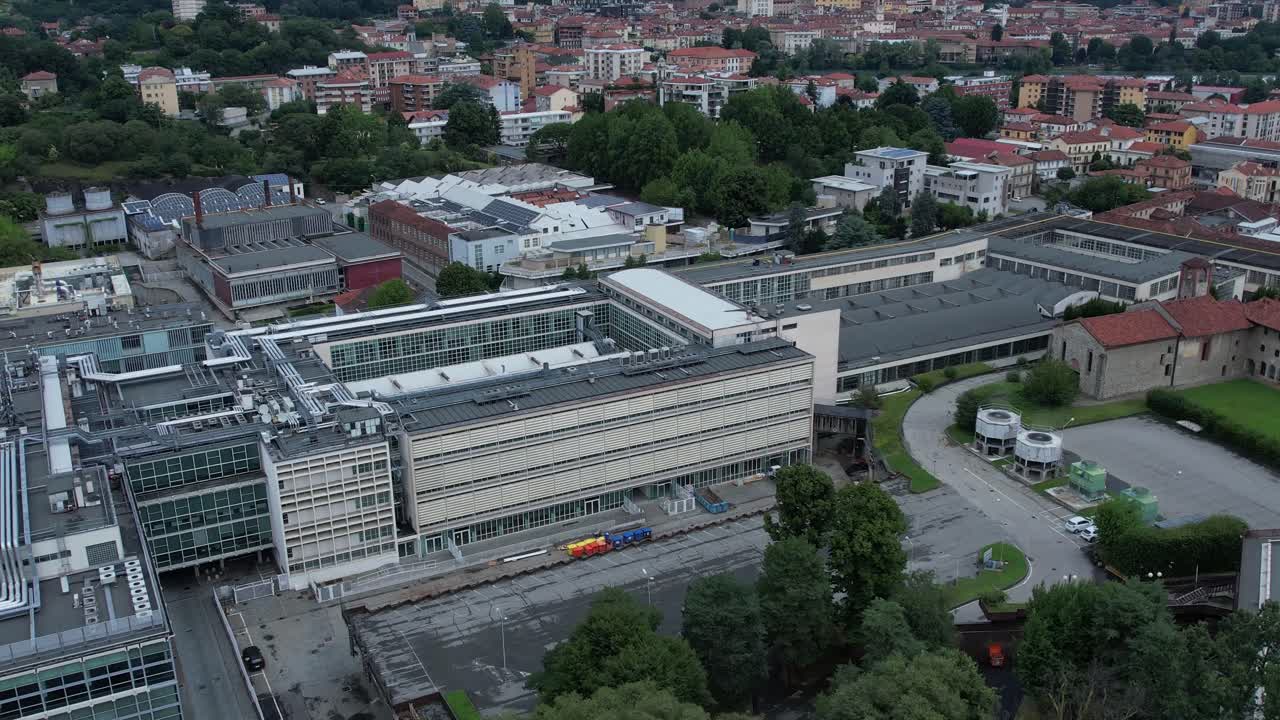Unesco-listed Olivetti district buildings in Ivrea's framed by the Alps and Mount Mombarone in the background, drone pan shot, slow motion, sunny and cloudy skym, Piedmont, Italy