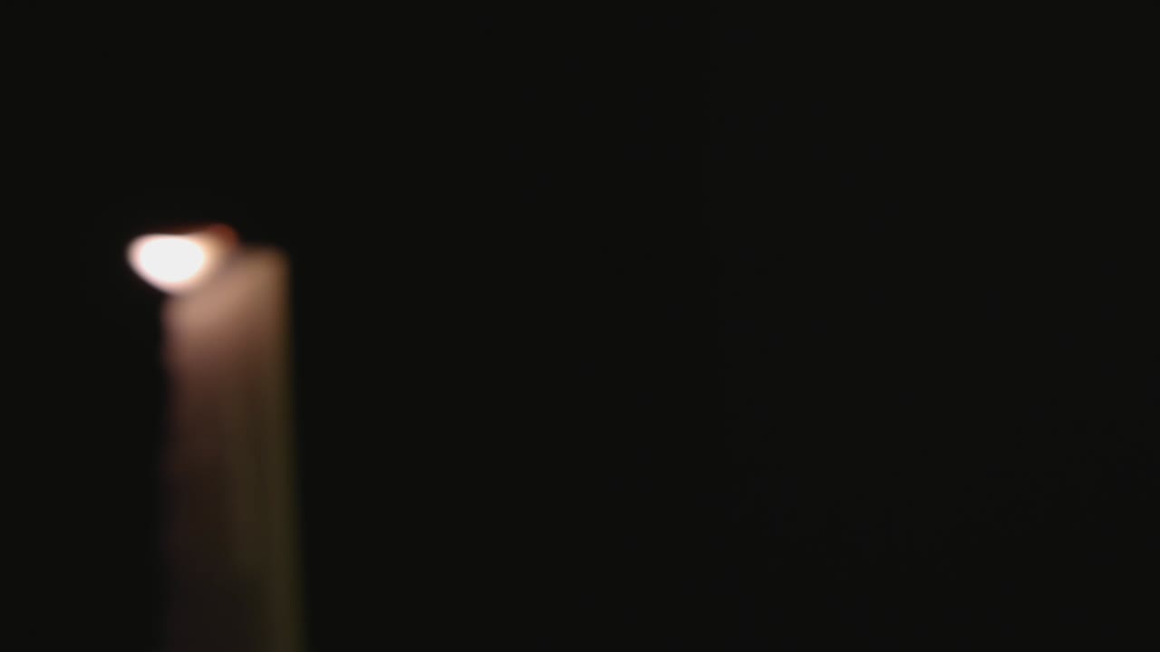 Fire hvide stearinlys tændt og en hurtig panorering hen over dem i slow motion.