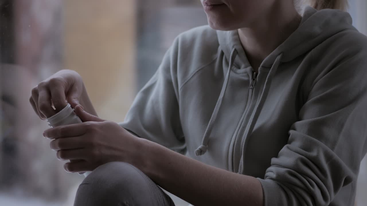 primer plano de una mujer abre un frasco de suplementos dietéticos y saca una cápsula