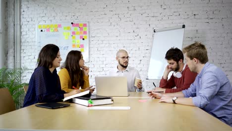 university professor sitting with four students in small classroom and teaching