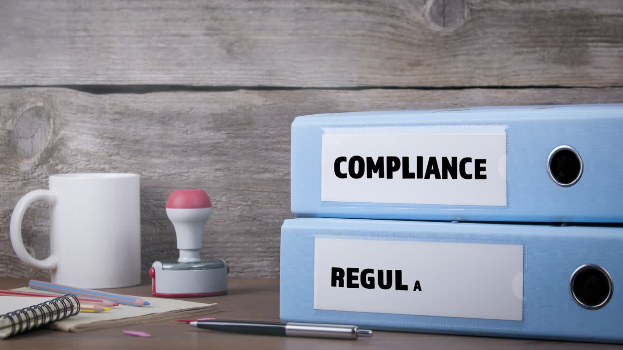 Compliance and Regulations concept. Office Binder on Wooden Desk