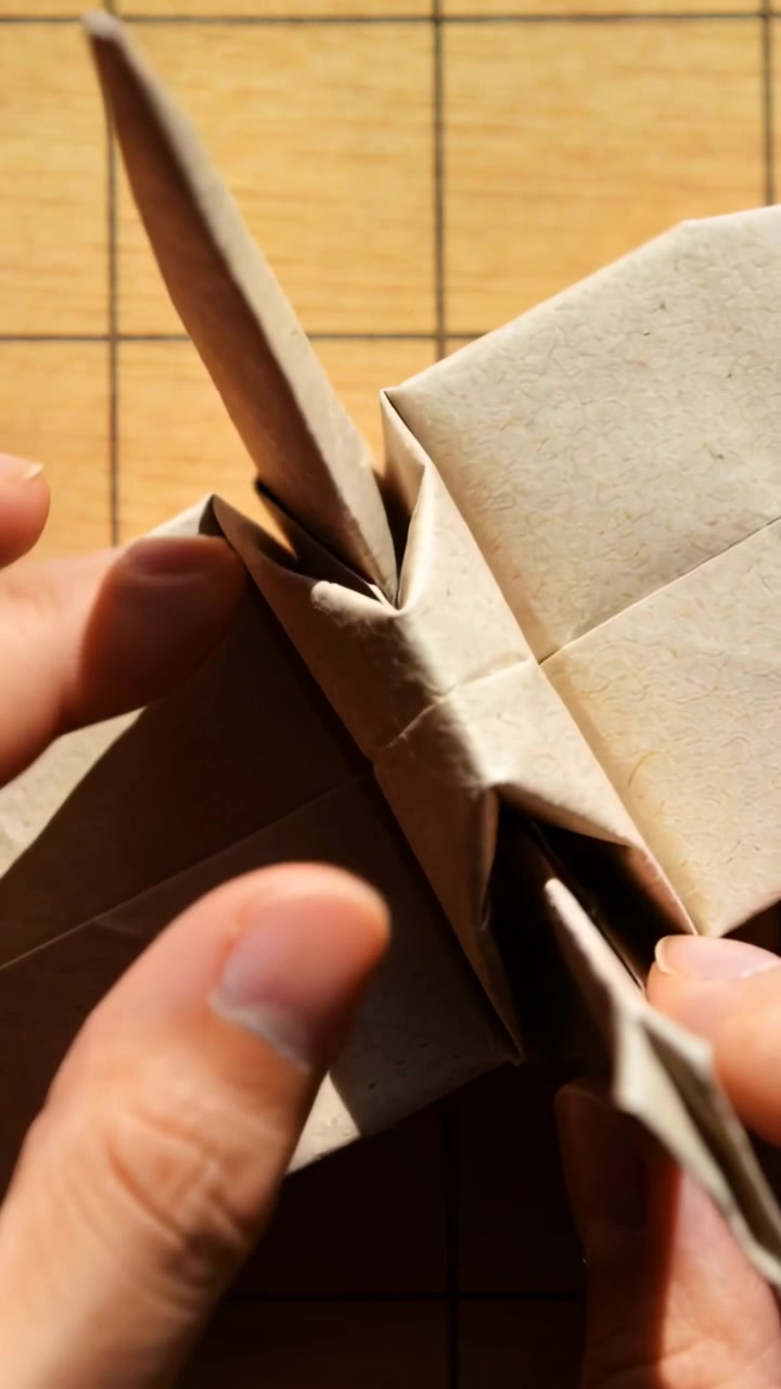 Video verticale: Tenendo un lembo, piegando con le dita carta kraft su un tappetino a griglia, bloccando gli strati