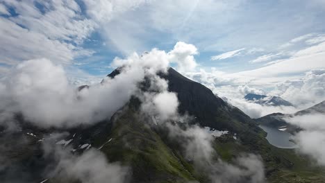 FPV-drone-drifts-amid-fluffy-clouds,-guiding-viewers-toward-a-looming-mountain-peak,-offering-a-surreal-journey-through-the-skies