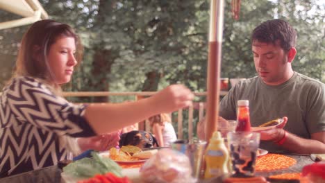 una familia comiendo una cena de barbacoa en su porche