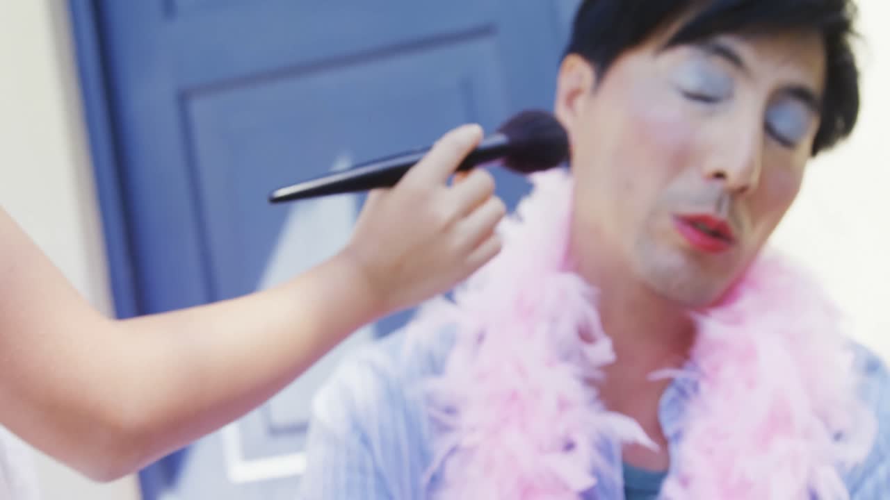 요정 의상 을 입은 귀여운 딸 이 아버지 의 얼굴 에 메이크업 을 하고 있다