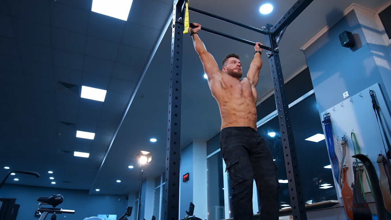 Strong athlete doing pull up. Muscular man doing exercises on horizontal bar in gym