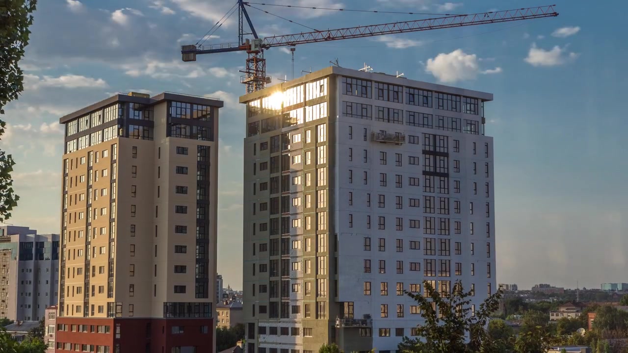 Gru e cantiere edile contro il cielo blu timelapse aereo. Operai che tinteggiano le pareti di una nuova casa residenziale