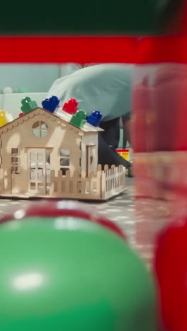 boy plays with plastic blocks while girl rocking baby doll. brother and sister enjoy toys in nursery view through clearance in construction of cubes, dolly zoom