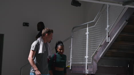 male and female athletes in fitness clothing training in gym walking down stairs to changing rooms before or after exercise