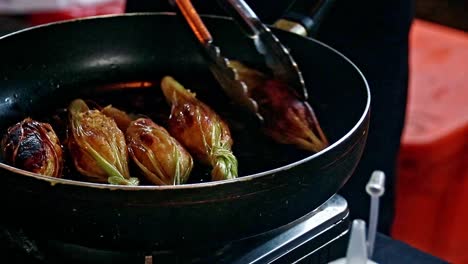 cook preparing a reimagined recipe of a traditional cambodian lemongrass beef skewers or sach ko jakak in a frying pan