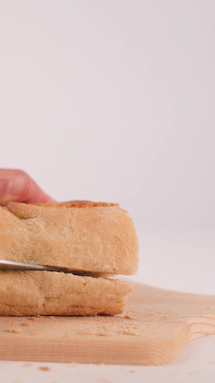 Hand Slicing Fresh Bread Loaf on Wooden Cutting Board