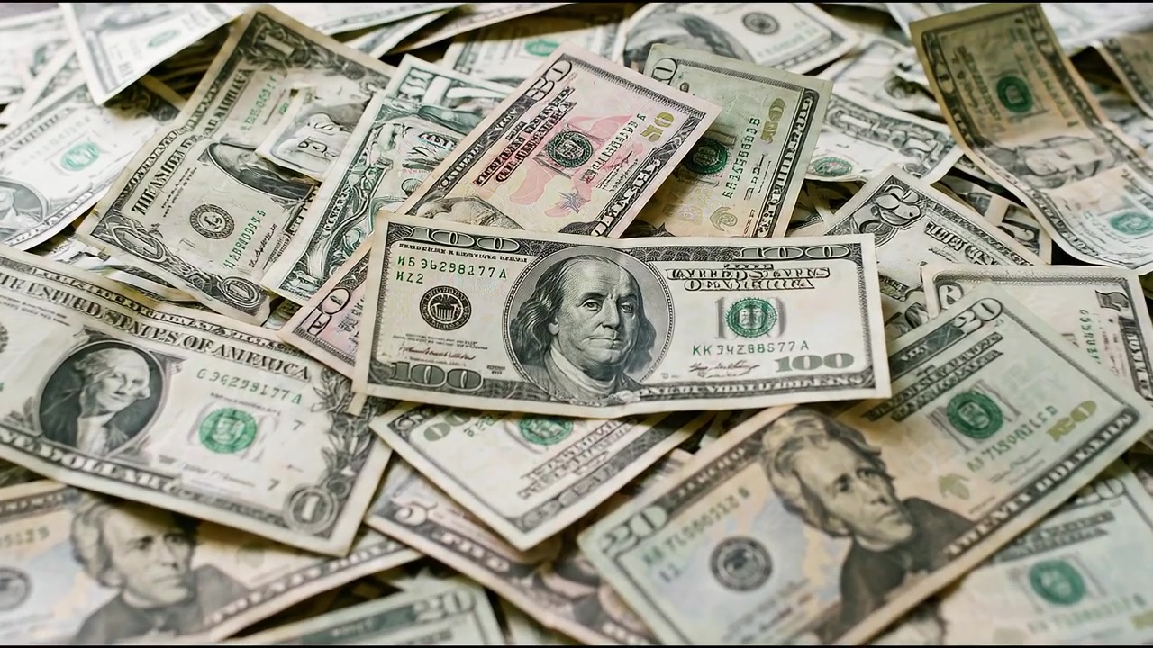 Gran pila de billetes de Estados Unidos esparcidos sobre una mesa, ilustrando abundancia y prosperidad financiera
