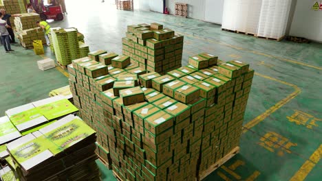 aerial view orbiting packed boxes of kiwi fruits for shipping inside a factory. shaanxi province, china