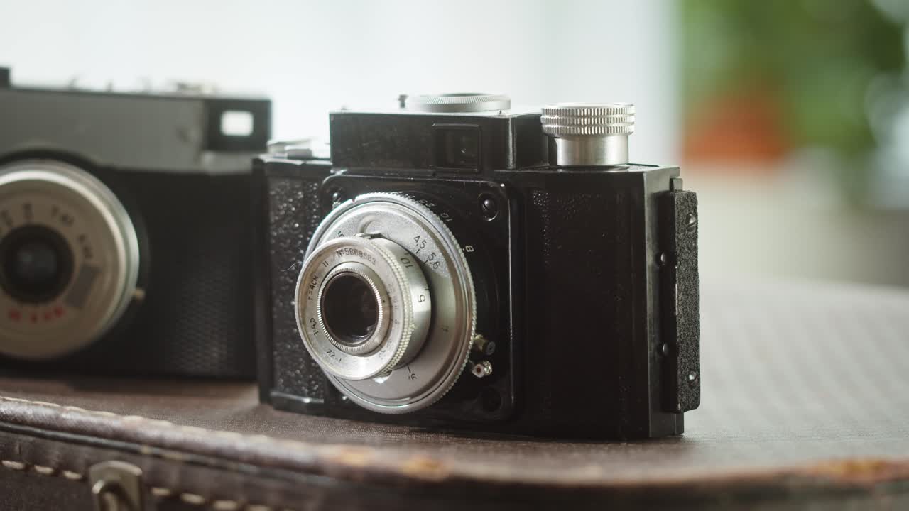 Cámara de película negra antigua con lente plateada sobre una maleta vintage