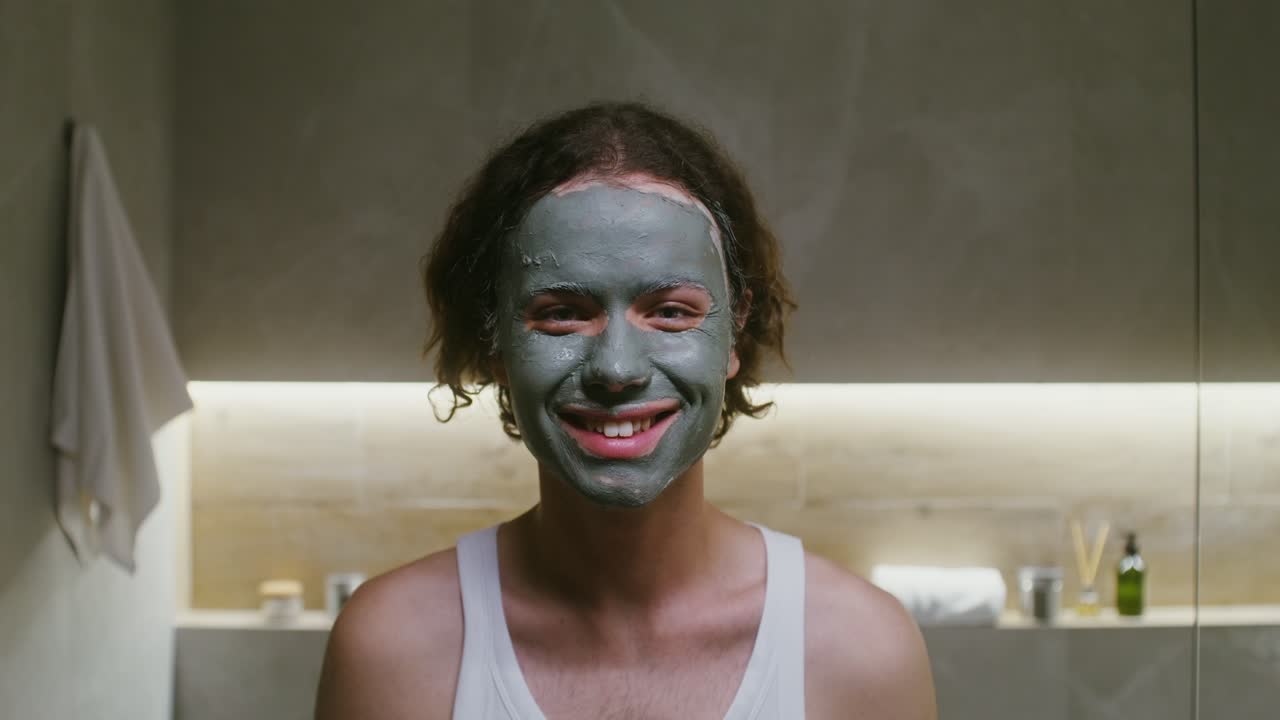 человек наносит глиняную маску в ванной