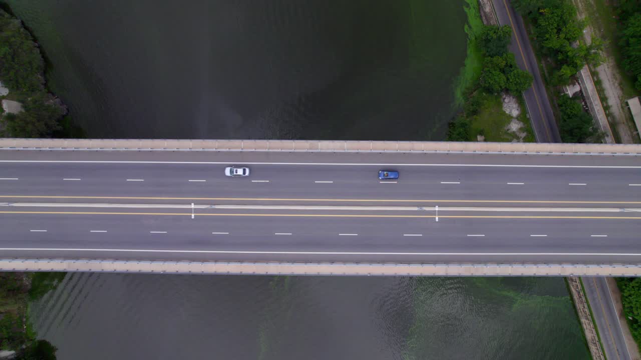 Aerial view of highway bridge over lake with cars moving on road