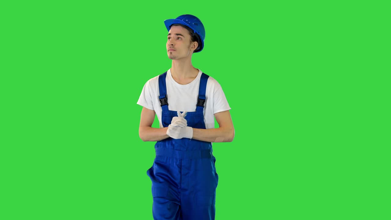 Confident young male builder walking looking to the sides on a Green Screen, Chroma Key