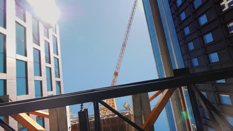 una enorme grúa de construcción cerca de edificios de oficinas con fachadas de vidrio edificio de la ciudad toma de steadicam
