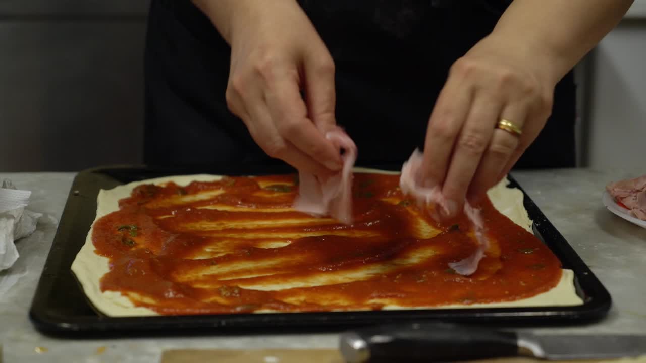 Close-Up of Hands Preparing Homemade Italian Pizza with Tomato Sauce and Ham