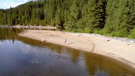 Woman-with-her-pet-dog-walking-near-river-coast-on-a-sunny-day-4k