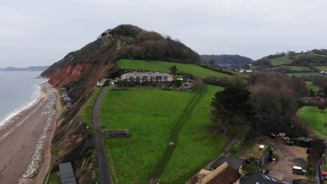 increíble zoom aéreo suave de 4k hacia arriba de la costa hacia las lujosas estructuras de la playa branscombe del reino unido