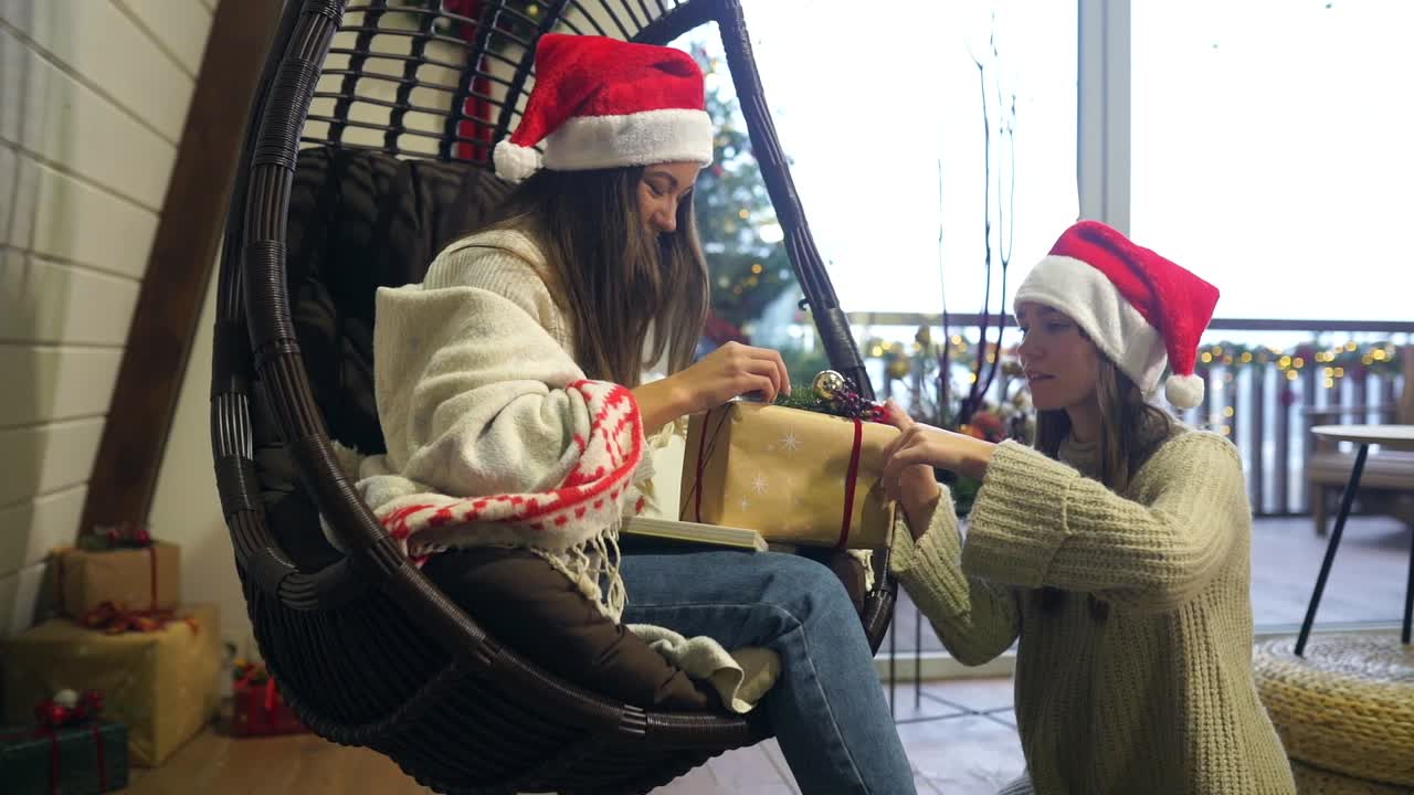 hermanas envolviendo regalos de navidad en una silla colgante