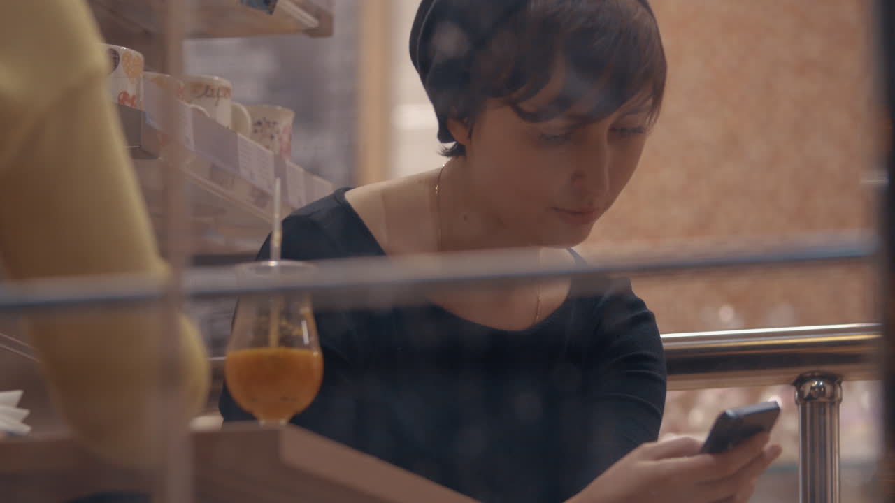 Donna che parla al cellulare mentre incontra un'amica al bar
