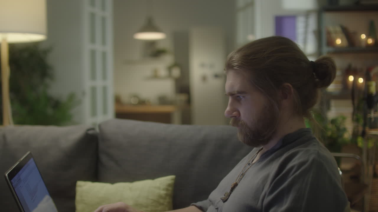 Mann bruker bærbar PC på sofaen hjemme
