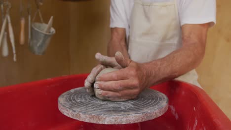 senior caucasian man wearing apron making pottery in his workshop