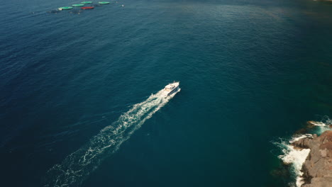 motorboat cruising at wild shore of madeira in stunning blue water, aerial