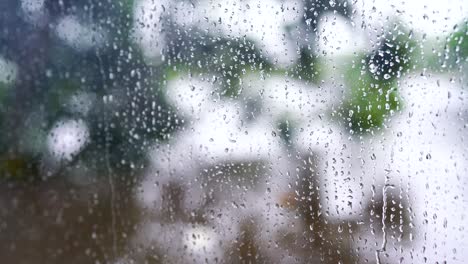 4k : close-up of rain drops splashing against a window glass with light leaks.