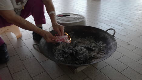 medium shot, put joss paper into the flame