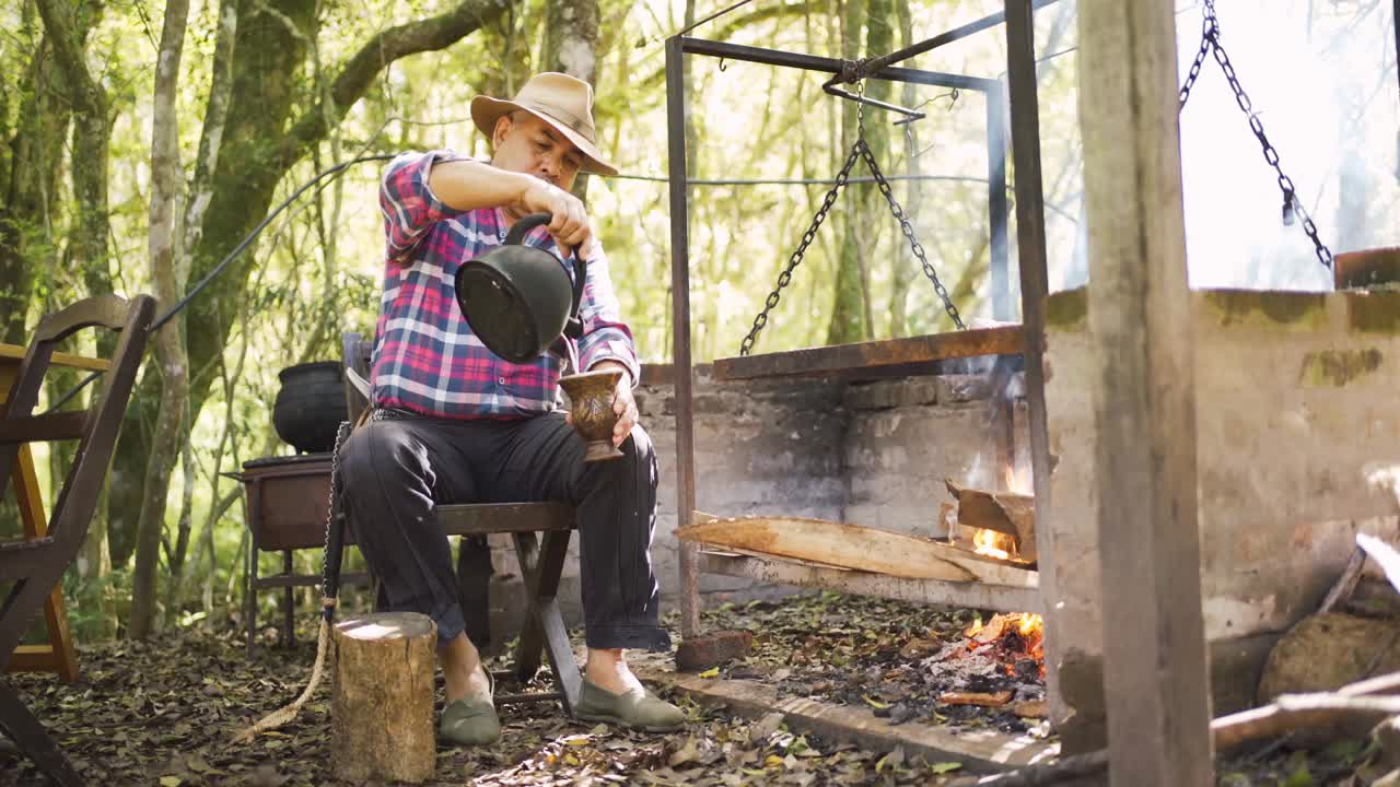 hombre étnico sirviendo compañero contra el estante de barbacoa en el jardín