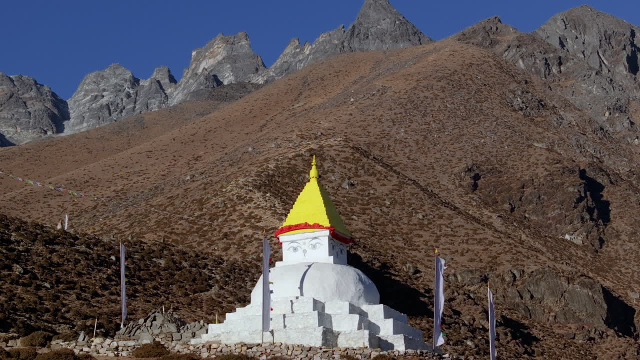 White Buddhist stupa in Nepal’s Everest Himalayan region with prayer flags fluttering in the wind. Snow-capped mountains form a serene backdrop, blending sacred architecture with alpine nature
