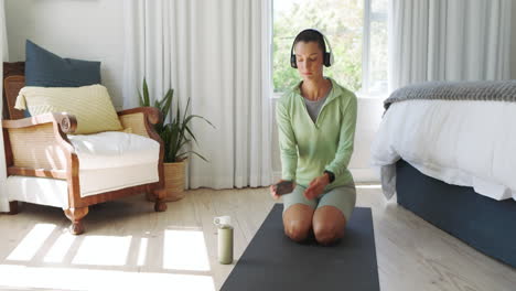 woman in green activewear using smartphone on yoga mat at home, staying focused