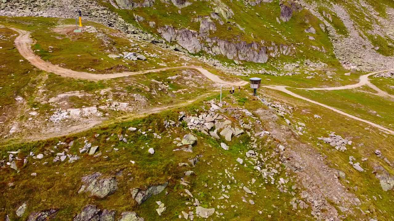 Aerial above scenic rocky mountain landscape in the swiss alps with hiking trails and watch tower. Remote landscape