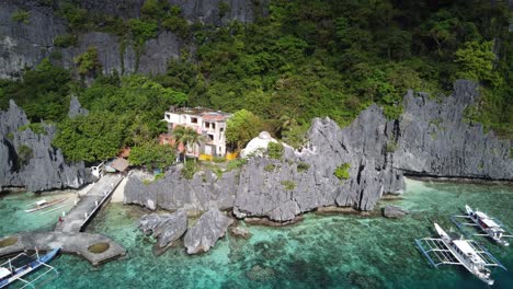 Matinloc-island-Tour-Boats-Pier-and-catholic-Shrine-resort-hidden-amid-jagged-Karst-rock-outcrops,-El-Nido