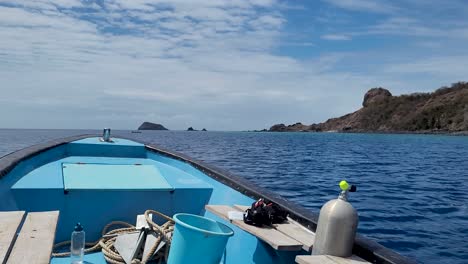 front of blue boat cruising on the sea next to an island during a clear sunny day