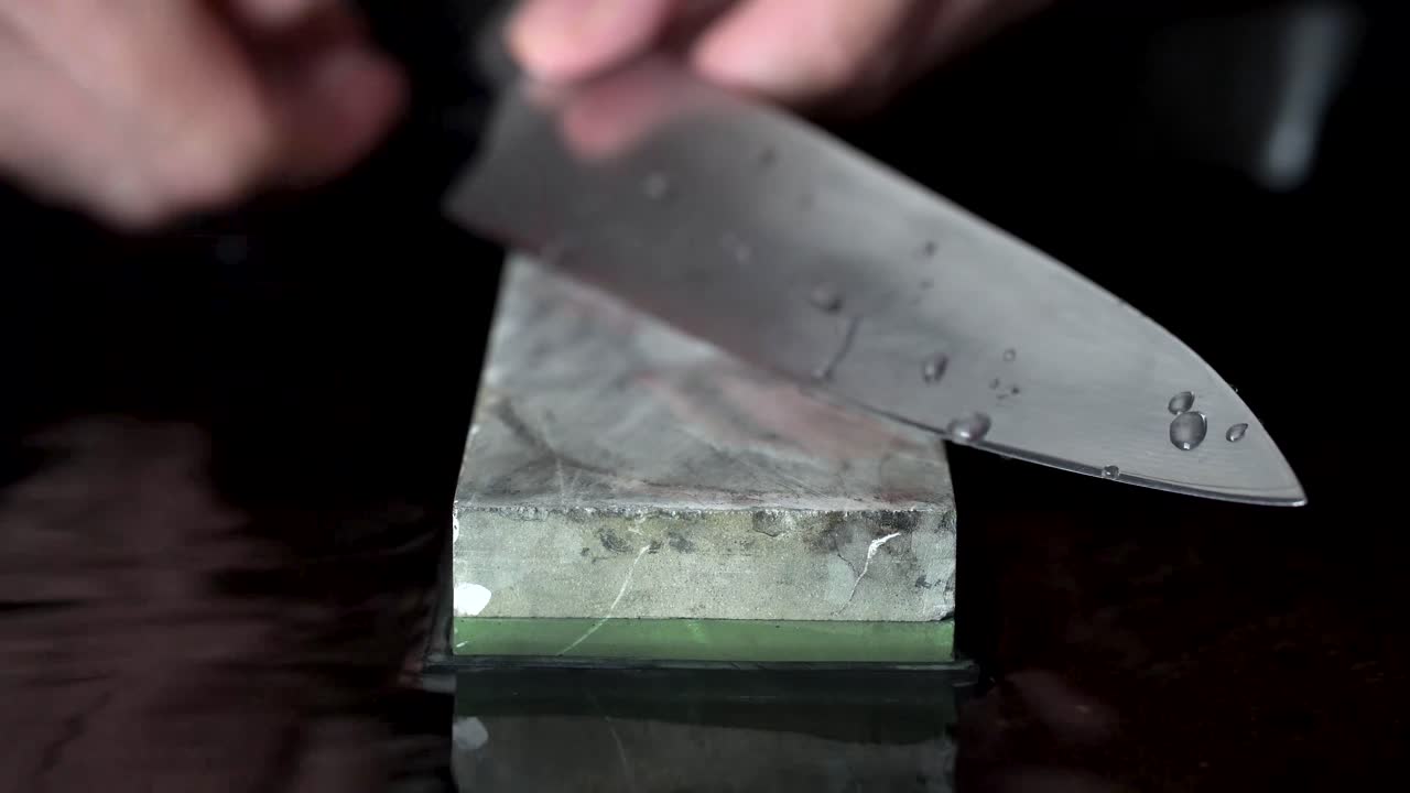 돌을 갈고 그 위에 물을 뿌릴 때 자파센 칼을 들고 있는 백인 남자의 손