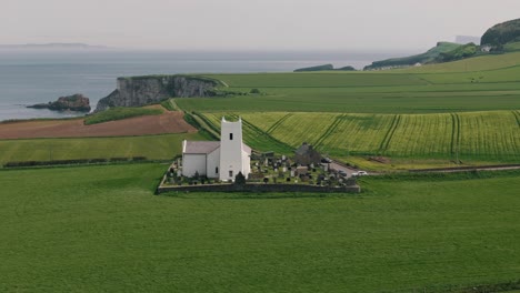 Toma-Aérea-En-Círculos-De-La-Iglesia-Costera-De-Irlanda-Del-Norte.