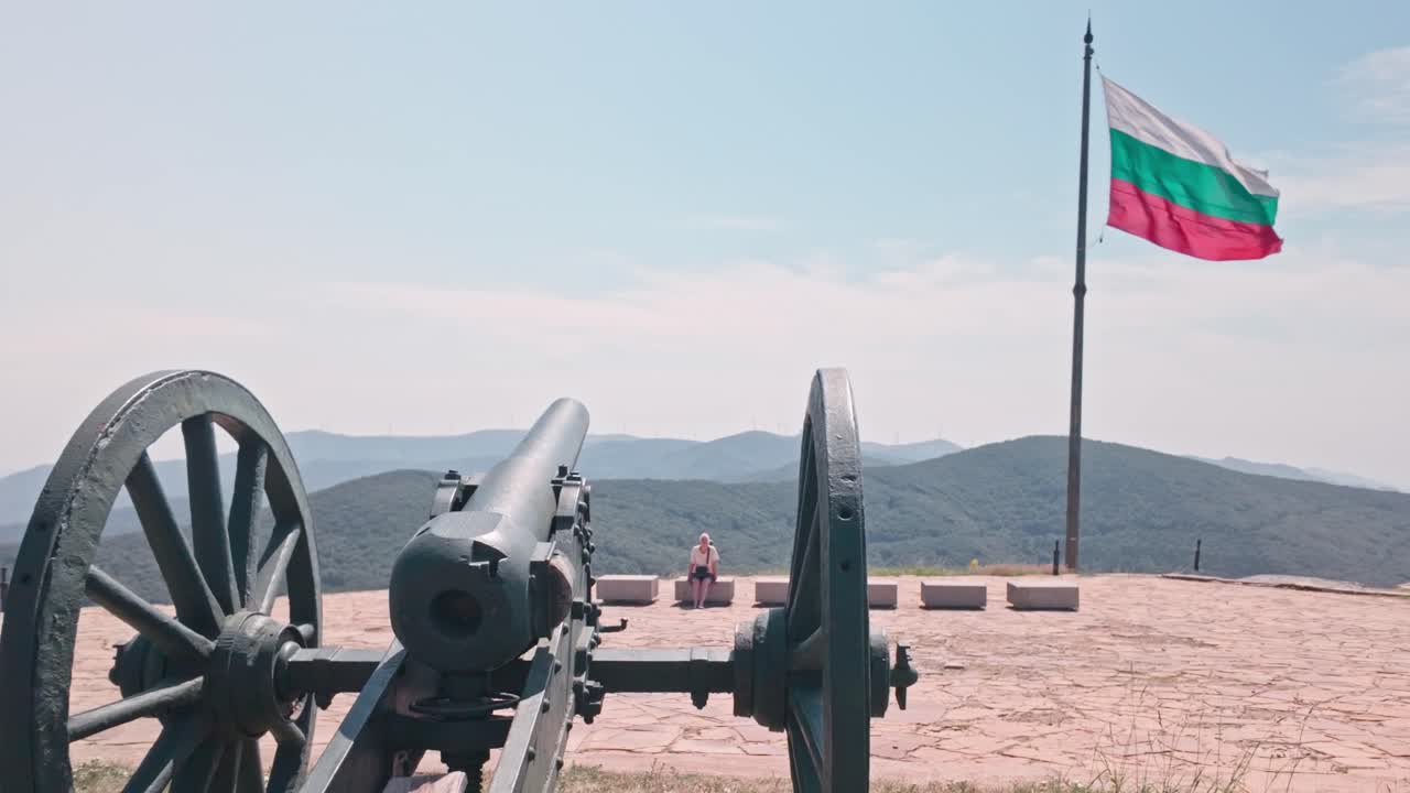 Bir dağ tepesinde tarihi top ve Bulgar bayrağı.