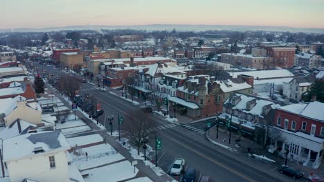 Toma-Aérea-De-La-Calle-Principal,-La-Pequeña-Ciudad-De-América,-Escaparates-Y-Casas-Coloniales-En-La-Ciudad-Histórica-De-Los-Estados-Unidos-Durante-La-Nieve-Del-Invierno